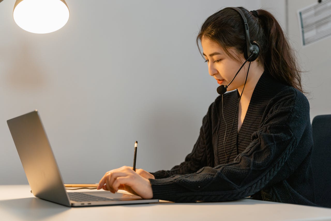 Focused call center agent working on a laptop with headphones. Customer service professional in an office setting.