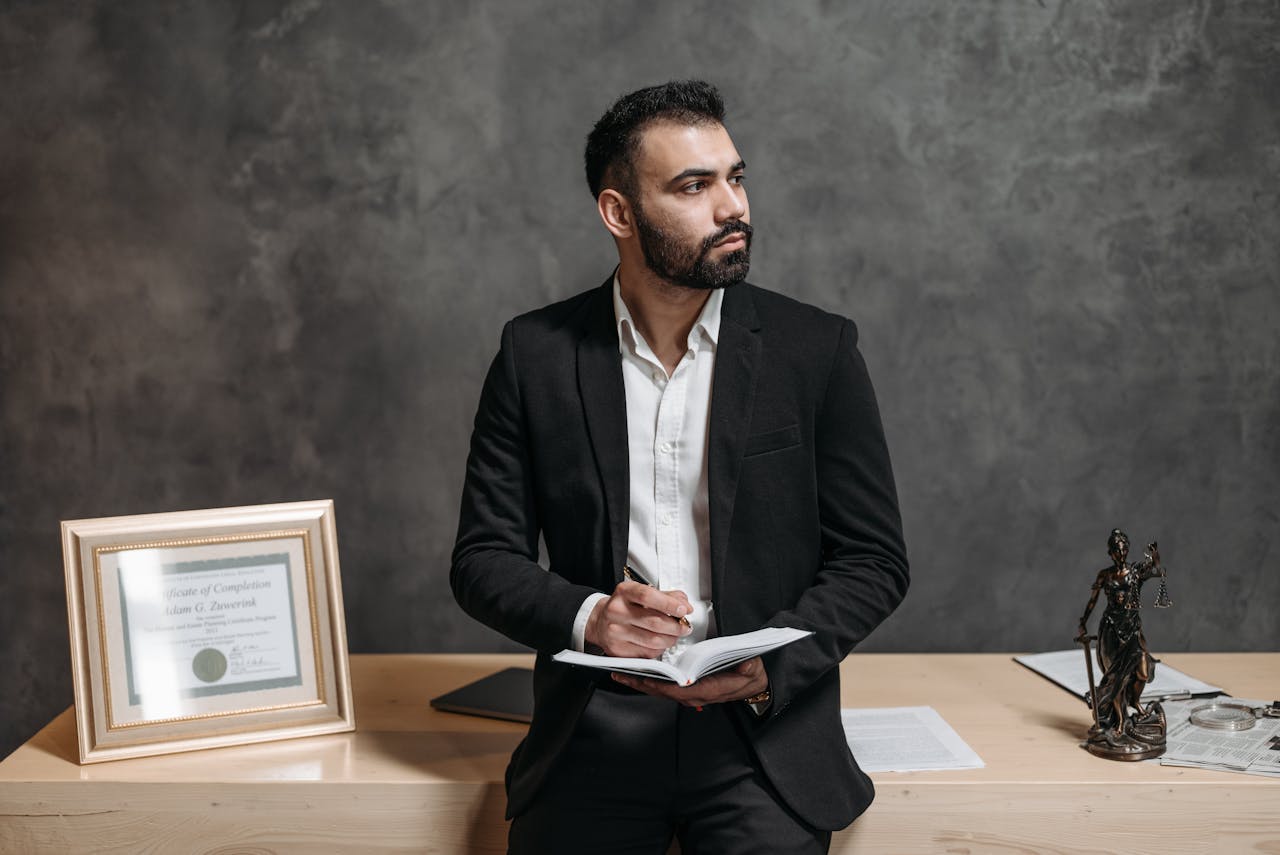 Confident male consultant takes notes, surrounded by legal paperwork in a modern office.